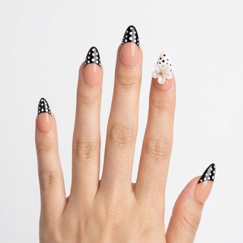 Hand with black and white polka dot nail designs on a plain background