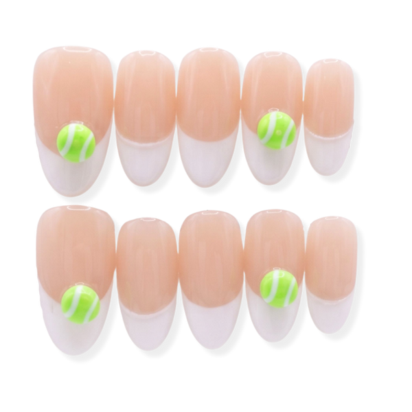 Tennis themed nails. U.S. Open themes nails. A set of ten press-on nails arranged in two rows of five, featuring a nude-peach top half and a white bottom half, with two green and white striped oval charms on the outer nails.