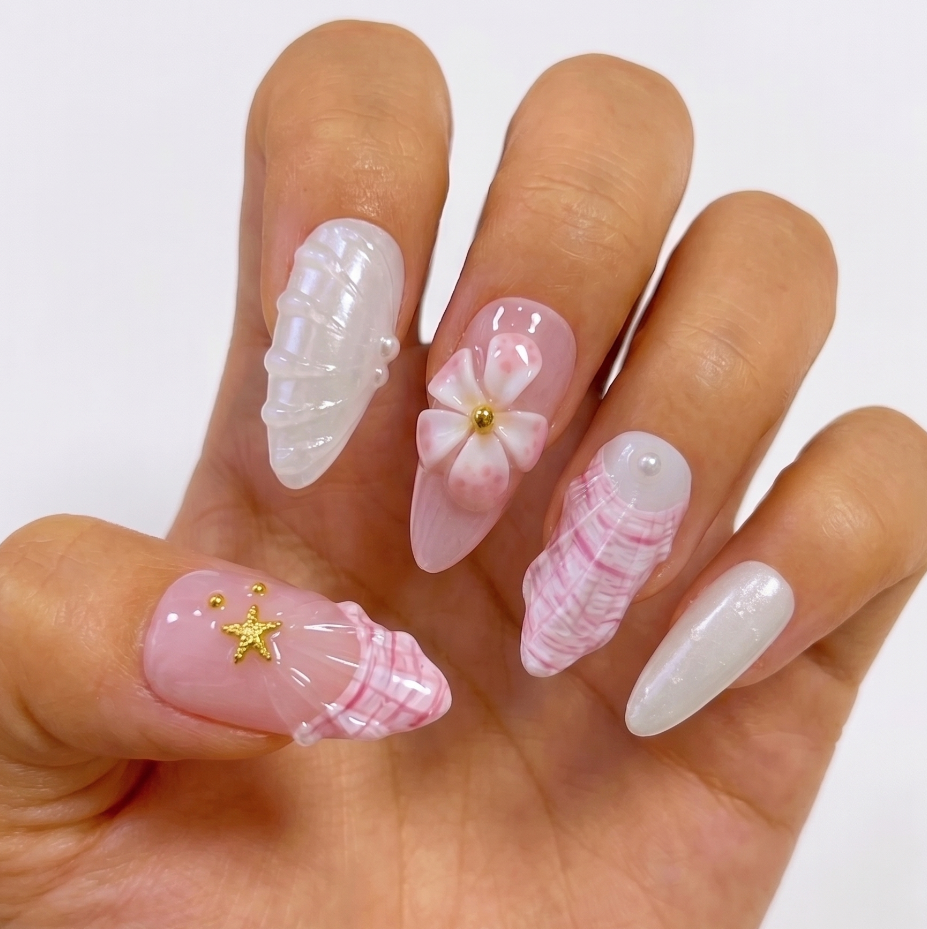 Hand with decorative nails featuring shells and flowers on a white background