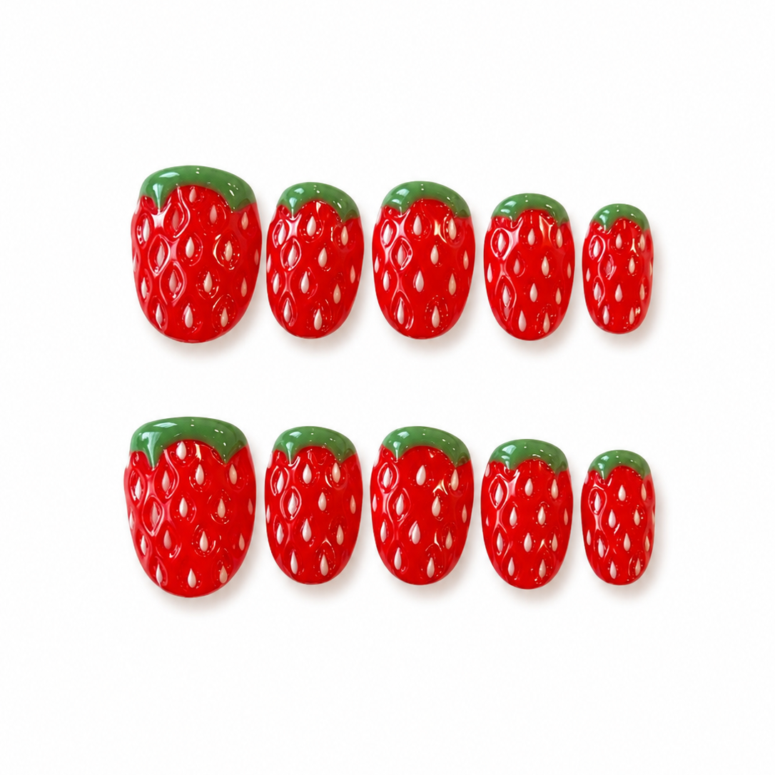 Red strawberry-shaped nail art decorations on a white background