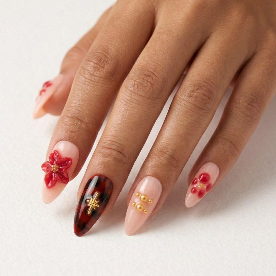 Hand with intricately designed nails featuring floral and gold accents on a light background