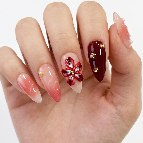 Hand with stylish nail art featuring a red flower design on a white background
