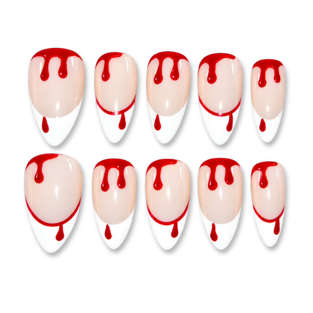Ten false press-on nails arranged in two rows of five on a plain white background. Each nail has a glossy nude-pink base with a white tip and red dripping paint detail across the top and around the middle.