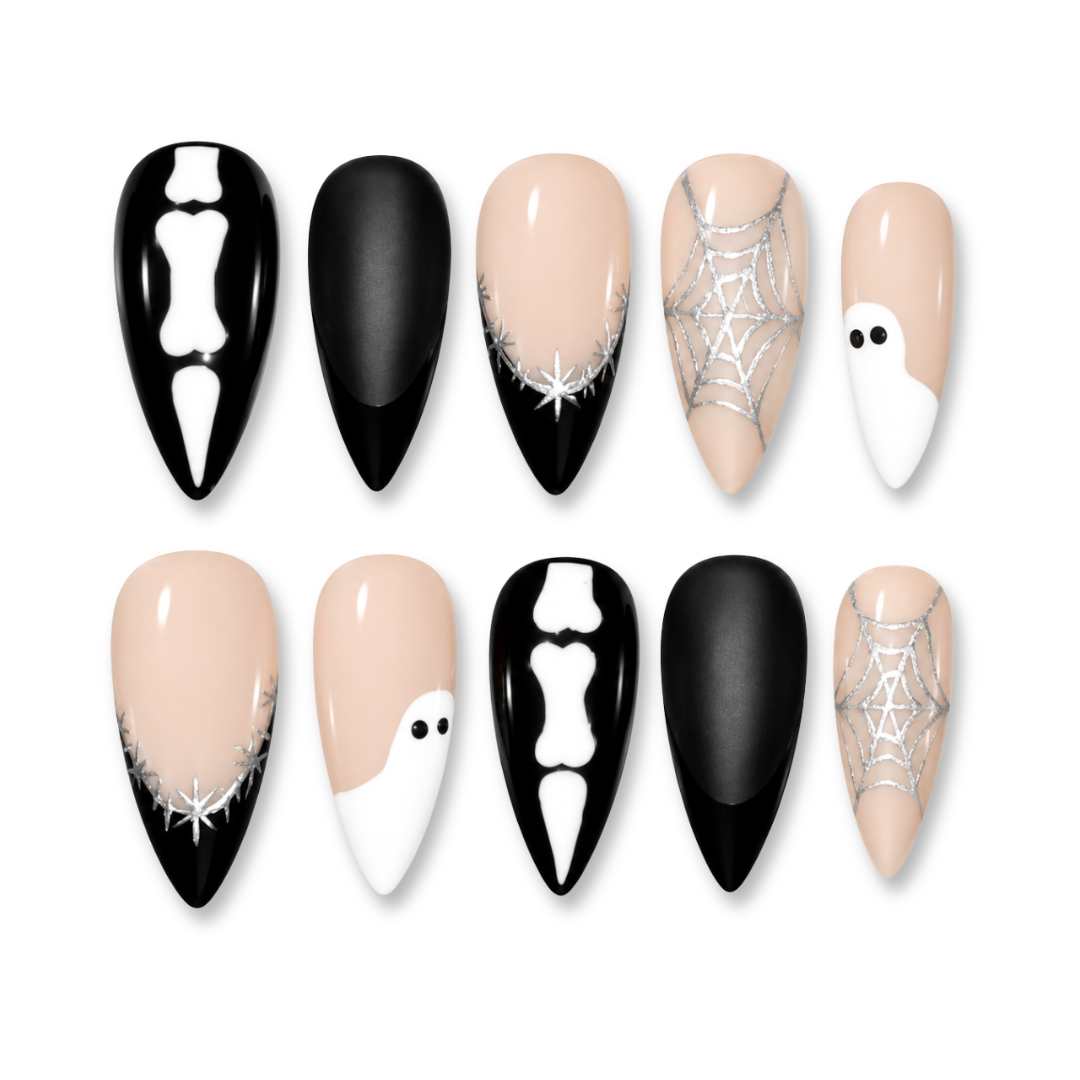 A set of ten press-on nails arranged in two rows of five on a plain white background. The nails feature Halloween-themed designs including black-and-white skeleton motifs, white ghosts on beige bases, silver spiderwebs, and solid black and nude beige nails.
