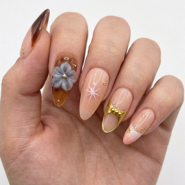 Hand with intricately designed nails featuring flowers and gold accents on a white background